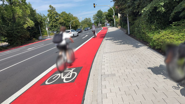  Im oberen Bereich der Rheiner Landstraße in Osnabrück (Krematorium) vor der Bushaltestelle wurde der Radschutzstreifen rot gekennzeichnet. Radfahrer fahren in Richtung stadteinwärts auf dem frisch lackierten Radschutzstreifen.