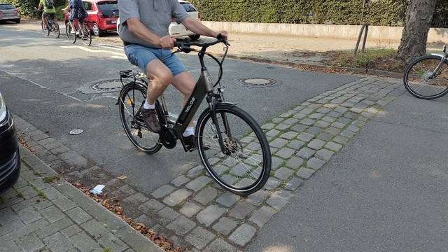 Radfahrer fährt über Kopfsteinpflaster an Ernst-Sievers-Straße in Osnabrück, das für Autos zur "Verkehrsberuhigung" gedacht ist. An den Seiten ist das Kopfsteinpflaster "abgesenkt".