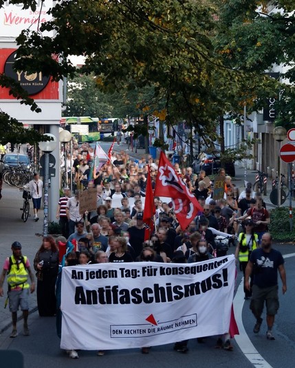 Demozug durch die Osnabrücker Innenstadt (Am Kamp).

Die Demospitze hält ein Banner. Bannertext: An jedem Tag: Für konsequenten Antifaschismus.
Den Rechten die Räume nehmen 