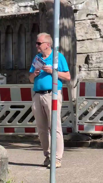 AfD Infostand Mitglied wippt und tappt am Haarmannsbrunnen in Osnabrück zur Musik der Gegendemo. 