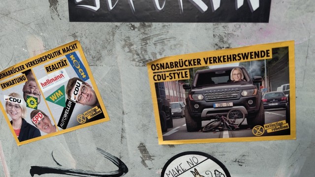 Sticker von extinction rebellion

Gelbe Umrandung 
Text: Osnabrücker Verkehrswende CDU Style

Bild(Montage)
SUV Frontansicht, Frau Pötter Kopf an der Fahrerposition. Unter dem SUV liegt ein zertrümmertes Fahrrad.