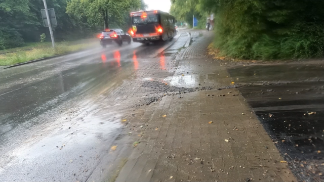 Kurt Schumacher Damm in Osnabrück. Von der Bredowstraße wurde ein Sanderdegemisch auf den Radschutzstreifen des Kurt Schumacher Damm gespült. Es fahren einige Autos und ein Bus vorbei. Ein Fahrradfahrer fährt durch das Sanderdegemisch.